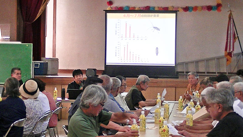 講習会で使用されたテキストや防除履歴の記入用紙、講師が身振り手振りに指示を出している手元のアップ